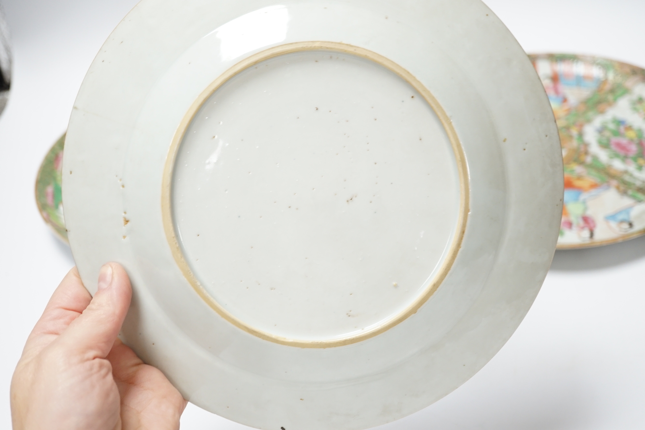 Two 19th century Chinese famille rose plates and an 18th century blue and white plate, 24cm in diameter